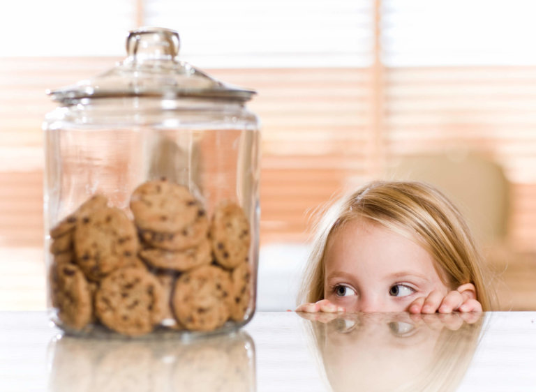 girl looking at cookies in a cookie jar